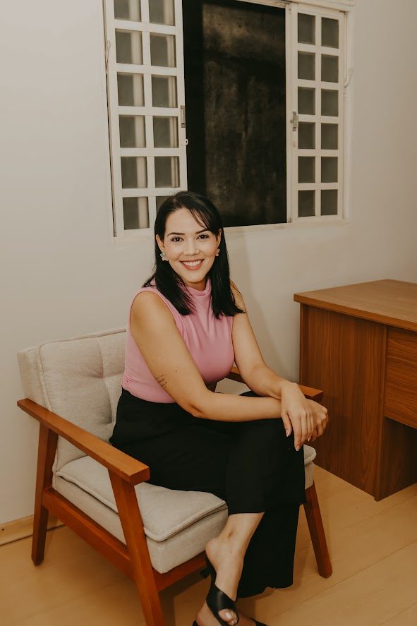 Dra. Graciele sorrindo, sentada em uma poltrona no consultório.